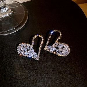 Close-up of heart-shaped earrings featuring zircons and starburst light effects