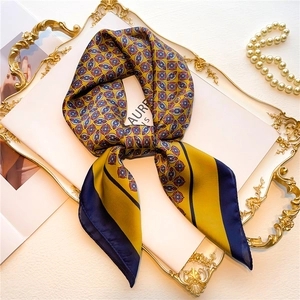 Detailed close-up of yellow and navy geometric silk scarf on an elegant golden tray