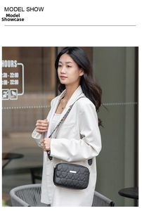 Detail shot of heart-quilted black camera bag with rainbow LOVE strap on white blazer