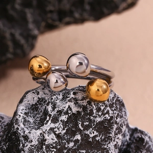 Macro shot of 18K gold and silver beaded open ring design on natural rock background