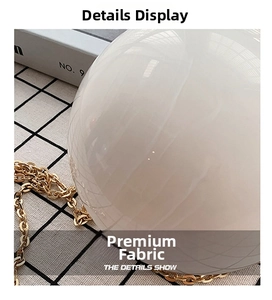 Detail of white spherical crossbody bag featuring a glossy finish and gold metal chain strap