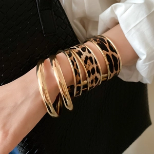 Gold-finish thin rings paired with a wide leopard print bangle for a modern chic look