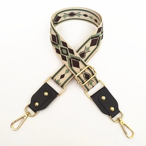 Close-up of adjustable woven strap with geometric patterns and gold metal swivel hooks