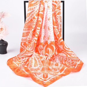 Chic orange and white paisley print satin square silk scarf on a minimalist display
