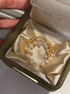 Detailed macro view of an elegant 24k gold-plated pearl brooch with sparkling crystals