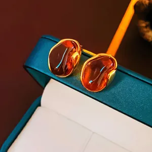 Detailed close-up of vintage geometric gold earrings with amber tiger eye resin inserts