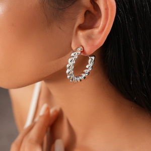 Close-up detail of silver chunky twisted rope hoop earrings on model ear