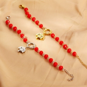 Detailed shot of Tree of Life pendant with red faceted beads on a silk background