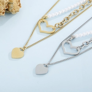 Detail of layered gold and silver chains with pearls and heart pendants on blue background