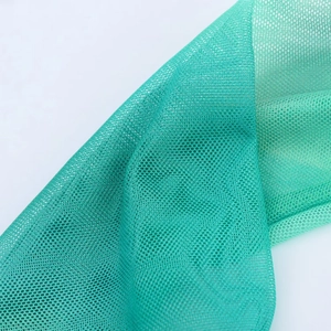 Detailed macro shot of breathable emerald green mesh fabric texture and layered netting