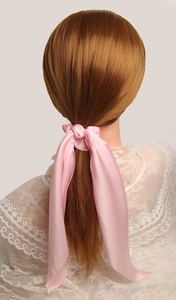 Pink satin ponytail holder with long streamers shown on model's hair from behind