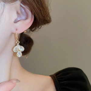Detailed close-up of teardrop cat-eye stone petal earrings with sparkling crystal accents