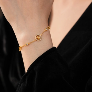 Detail of a gold-plated bracelet with a zircon star compass charm on a wrist