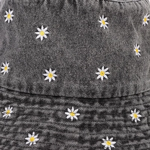 Detail view of white daisy embroidery and premium denim texture on the dark gray sun hat