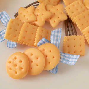 Cute simulation biscuit hair clips with blue checkered bows on a clean background
