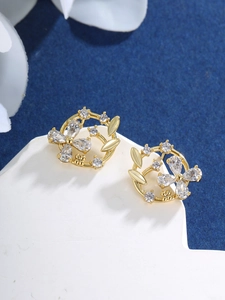 Macro shot of gold-plated floral earrings with sparkling cubic zirconia on stone base