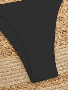 Detail of black matte swimwear fabric on a woven straw mat, featuring precise stitching