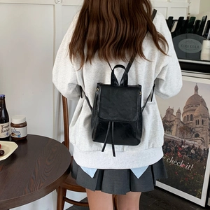 Mini zaino nero in pelle PU con chiusura a coulisse e patta indossato da una modella