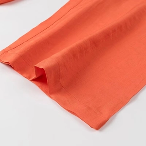 Détail de la texture du tissu orange et coutures professionnelles sur le pantalon large