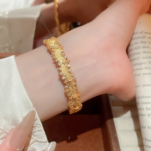 Detail view of a gold-plated bangle with brushed texture and sparkling zircon inlay for women