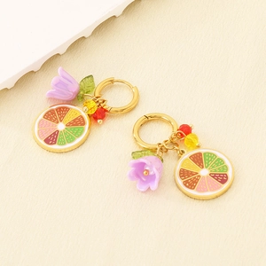Detail of stainless steel hoop earrings with colorful lemon fruit and flower pendants