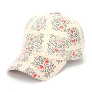 Detailed close-up of ivory baseball cap featuring black grid and red sunburst embroidery