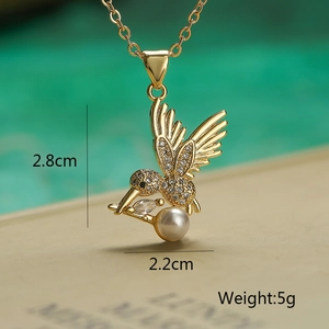 Macro detail of gold hummingbird pendant with clear crystals and pearl size measurements