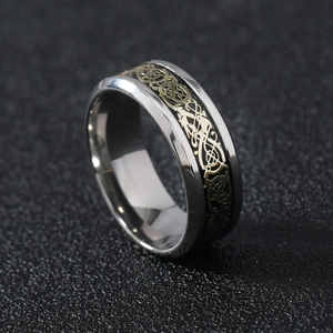 Detail of men's stainless steel ring featuring a gold Celtic dragon pattern on black inlay