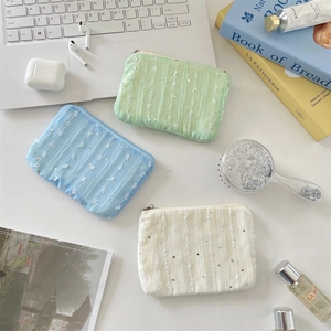 Chiffon floral coin purse with sequins and zipper on white desk with beauty items