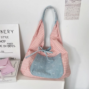 Detailed close-up of pink checkered tote bag featuring a blue denim bow pocket design