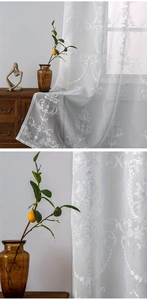 Detailed view of white lace curtains with classical embroidery and elegant sheer texture