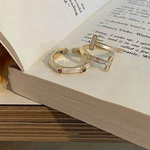 Vintage gold rings with enamel colorful gemstones and T-shape design on a book