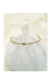 Detailed macro of gold chain tennis bracelet with blue gemstone and cubic zirconia