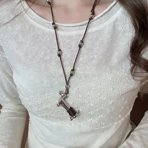 Detail of dachshund pendant necklace with wax rope wrap on model wearing white lace
