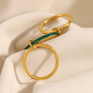 Close-up of triple-layered 18K gold-plated interlocking rings with emerald green gemstone