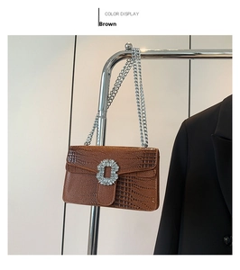Close-up of brown crocodile pattern handbag with crystal buckle and silver chain
