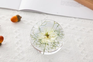 Detail view of dandelion crystal ball resin paperweight with white flower on fabric