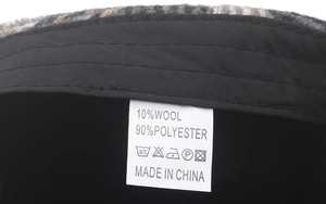 Detail of wool blend fabric label showing material composition on men's plaid beret cap