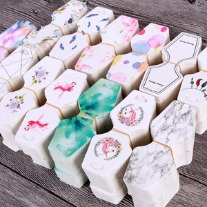 Various jewelry display cards with marble and floral patterns on a wooden surface