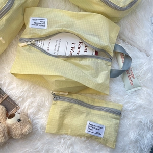 Macro detail of pale yellow checkered waterproof travel organizers on soft white plush surface