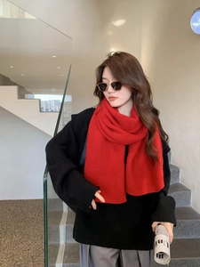 Detail of red knitted checkerboard scarf showing thick textured pattern on a model