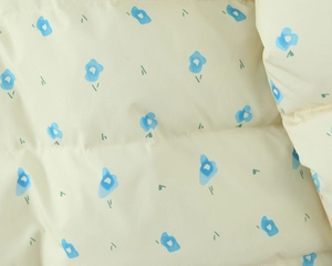 Detail shot of beige floral cotton jacket fabric with blue flowers and quilted stitching