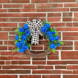 Detailed close-up of blue rose Christmas wreath with a checkered bow on brick wall