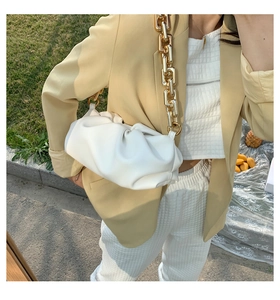 Close-up of white pleated cloud bag with chunky gold chain strap for stylish outfit