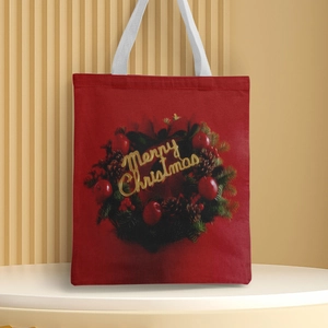 Close-up of red canvas Christmas tote bag with wreath and golden Merry Christmas text