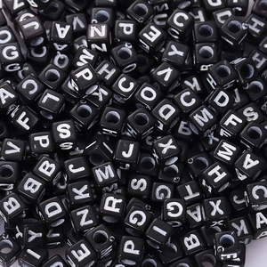 Macro shot of black acrylic cube beads with white printed letters for DIY jewelry making