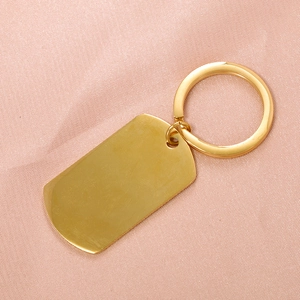 Polished gold stainless steel rectangle military dog tag keychain on pink satin background