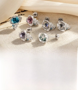 Macro detail of ocean series sea star and conch studs with zircon inlays on fabric