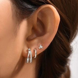 Close-up of 925 sterling silver geometric butterfly stud and hoop earrings set on ear