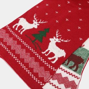 Macro shot of Christmas scarf with red reindeer, tree, and snowflake knitted patterns